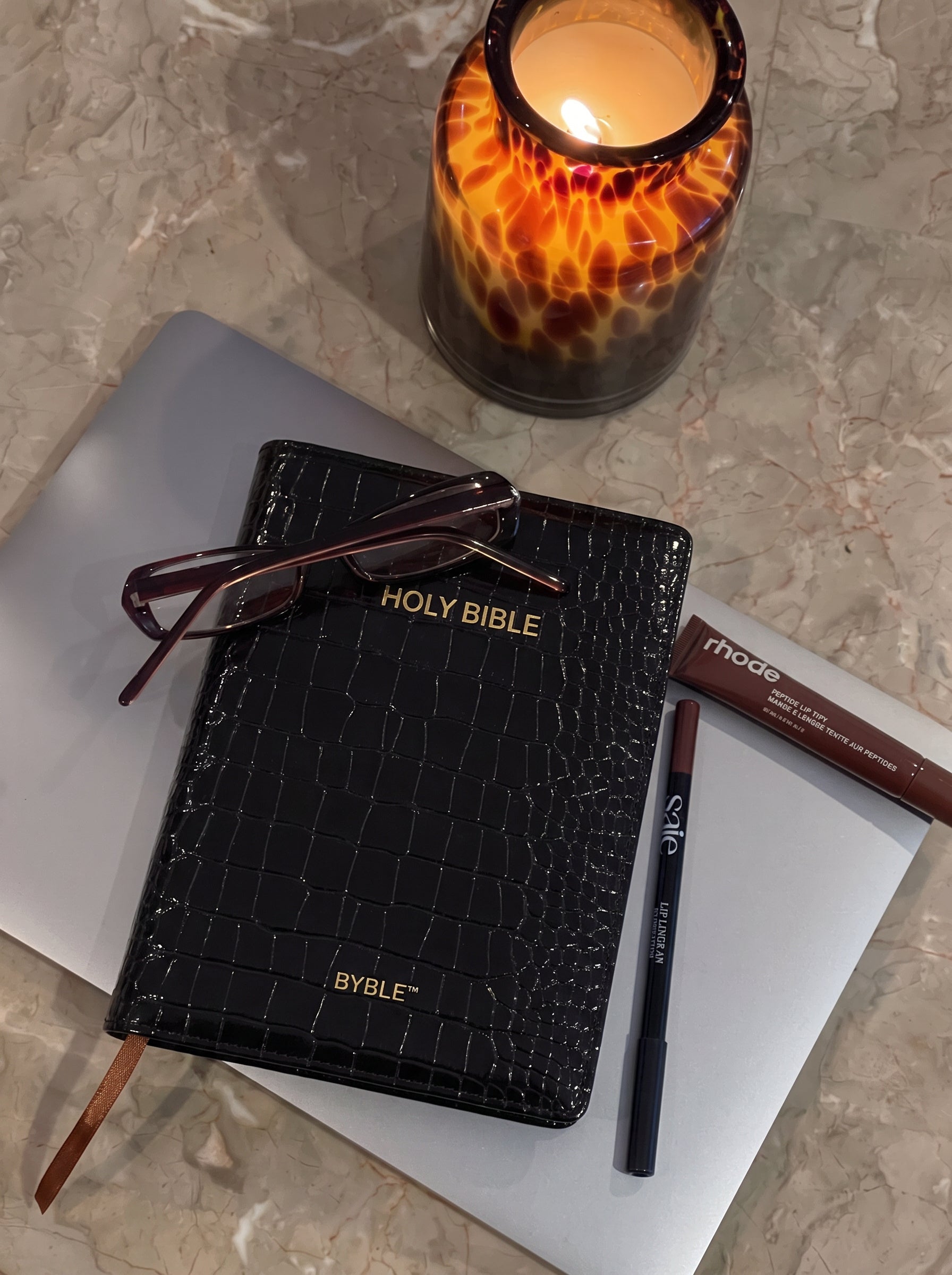 Black Everyday Bible Cover beside a candle and reading glasses