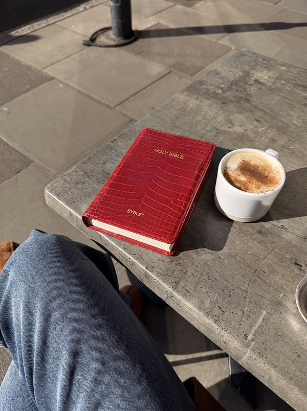 Red Everyday Bible Cover on a cafe table with a coffee